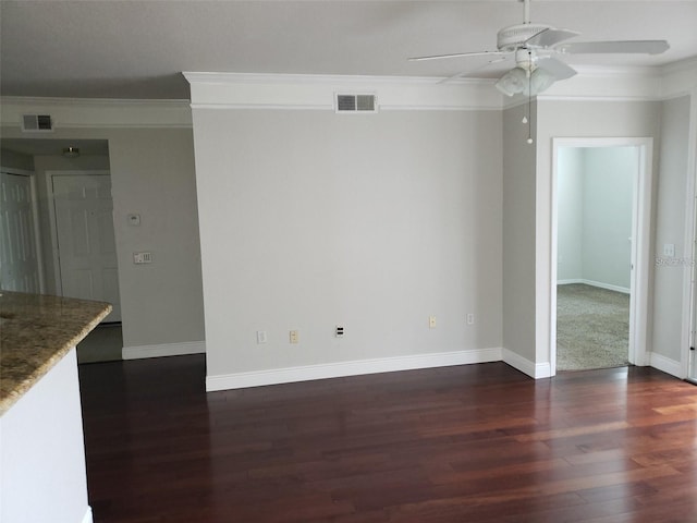 spare room featuring baseboards, visible vents, dark wood-style flooring, and crown molding