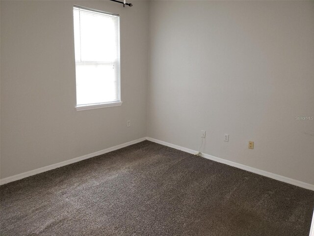 carpeted empty room featuring baseboards