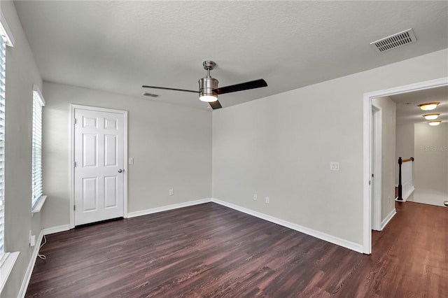 empty room featuring ceiling fan, a healthy amount of sunlight, and dark hardwood / wood-style flooring