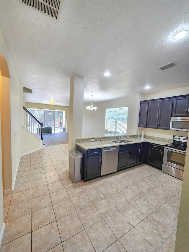 kitchen with sink, appliances with stainless steel finishes, hanging light fixtures, a notable chandelier, and light tile patterned flooring