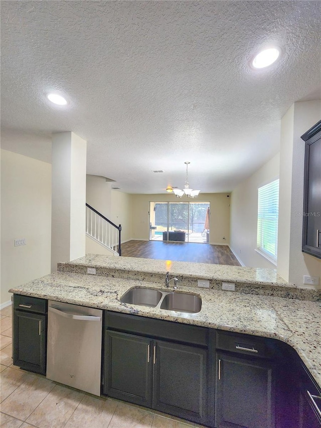 kitchen with sink, light stone counters, light tile patterned floors, dishwasher, and a notable chandelier