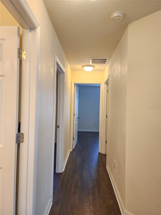 hall with dark hardwood / wood-style flooring and a textured ceiling