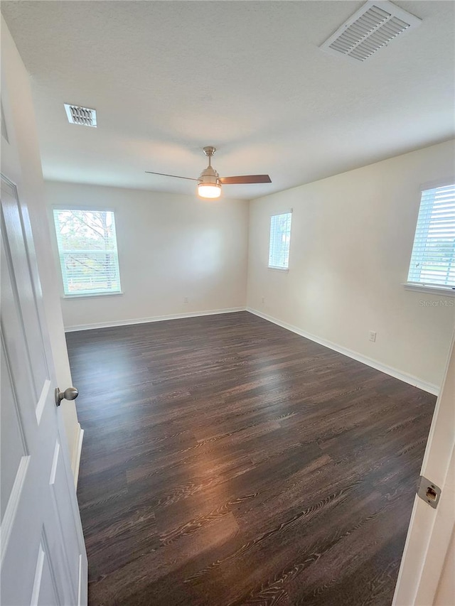 empty room featuring dark hardwood / wood-style flooring, plenty of natural light, and ceiling fan