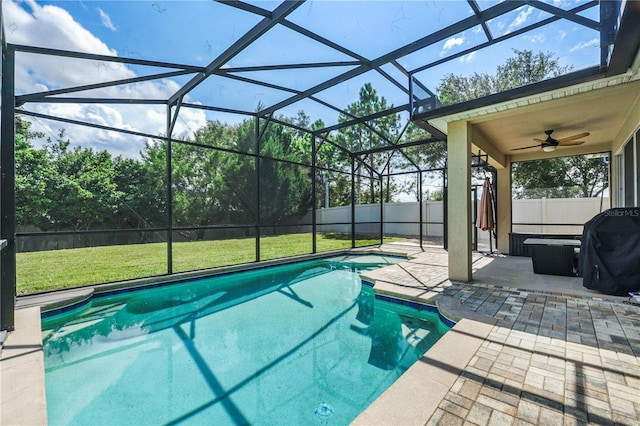 view of swimming pool with ceiling fan, a patio, glass enclosure, and a lawn