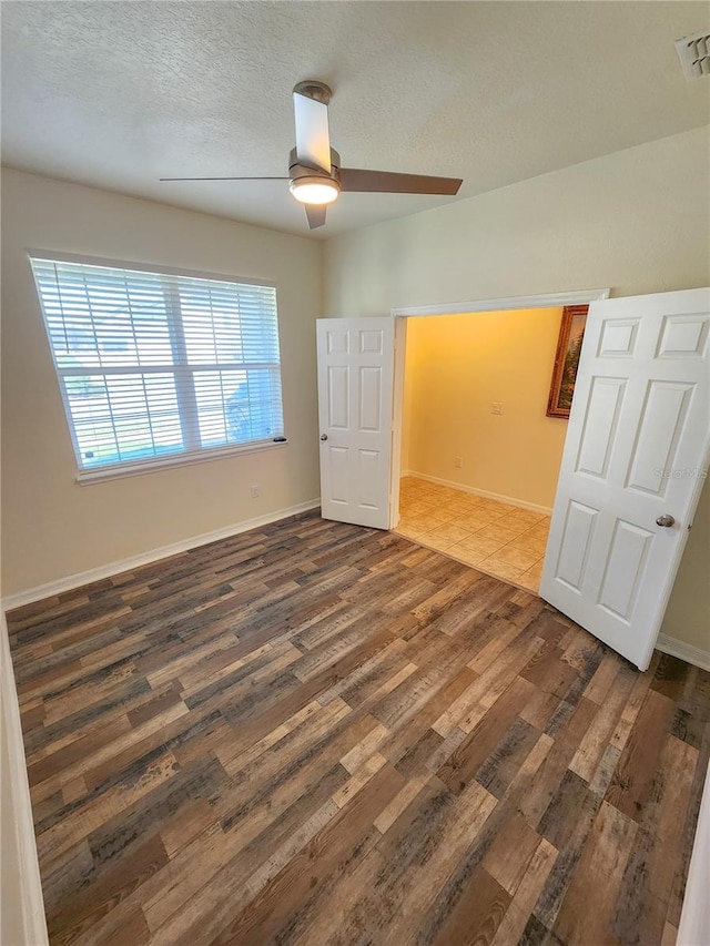 unfurnished bedroom featuring a textured ceiling, dark hardwood / wood-style floors, and ceiling fan