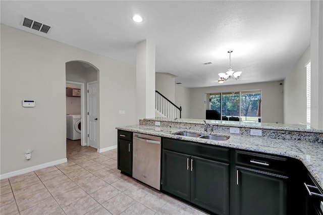 kitchen with light stone countertops, washer / dryer, stainless steel dishwasher, decorative light fixtures, and sink