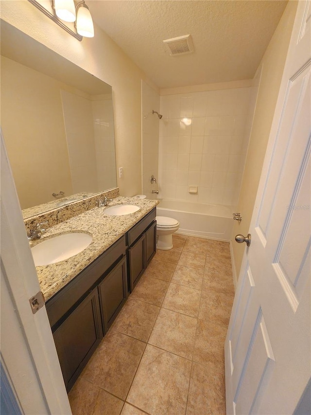 full bathroom with tile patterned flooring, tiled shower / bath, toilet, a textured ceiling, and vanity