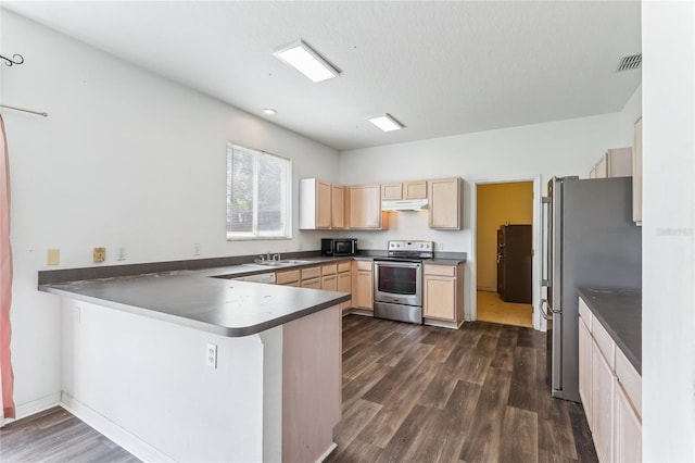 kitchen featuring dark countertops, dark wood-style floors, appliances with stainless steel finishes, a peninsula, and under cabinet range hood