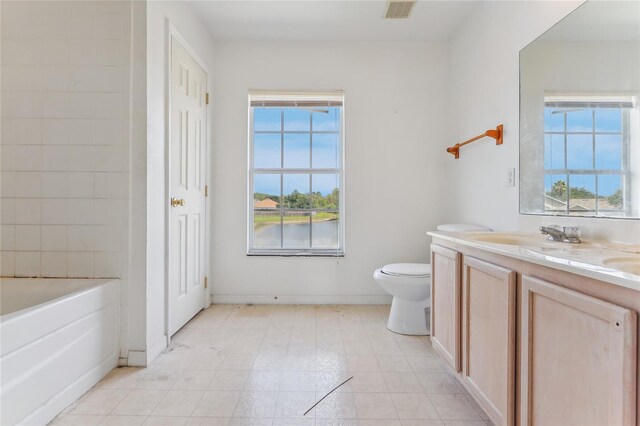 bathroom with vanity, a tub to relax in, tile patterned floors, and a healthy amount of sunlight