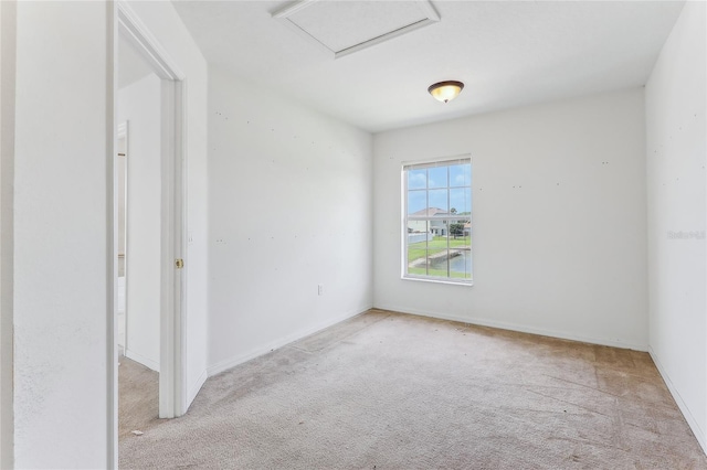 empty room with baseboards, attic access, and light colored carpet