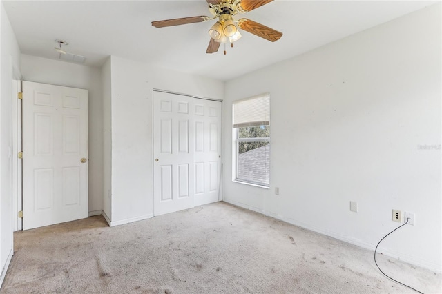 unfurnished bedroom featuring ceiling fan, light colored carpet, and a closet