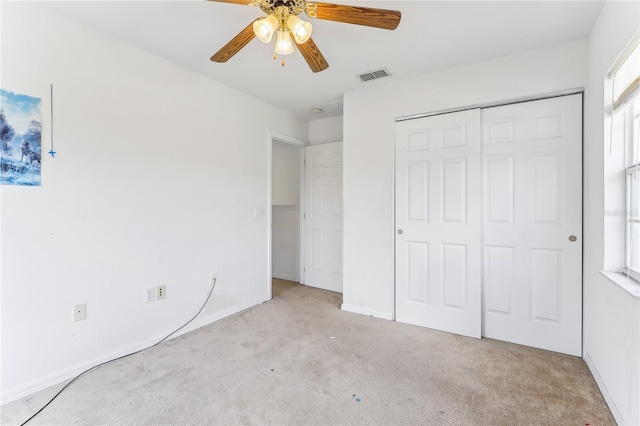 unfurnished bedroom featuring a ceiling fan, visible vents, a closet, and light colored carpet