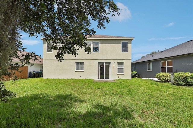 back of property with a lawn and stucco siding