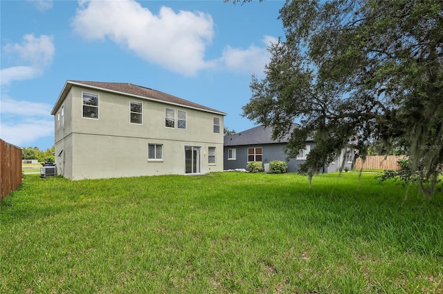 rear view of house with fence, cooling unit, and a yard