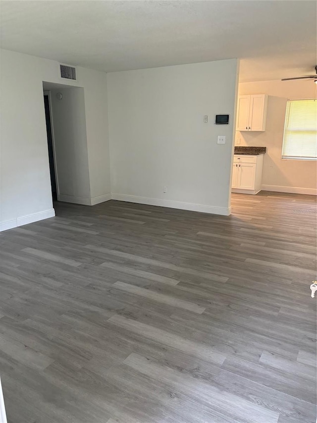 empty room with wood finished floors, visible vents, and baseboards