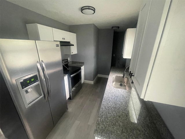 kitchen featuring under cabinet range hood, stainless steel appliances, a sink, light wood-style floors, and white cabinets