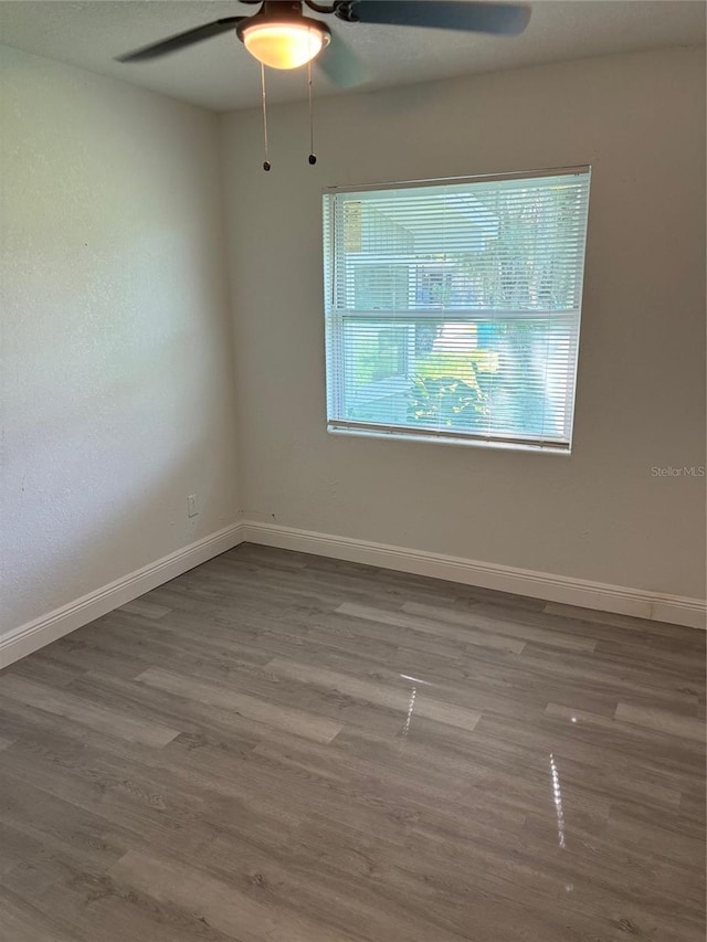 spare room with ceiling fan, baseboards, and wood finished floors