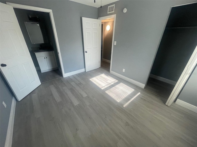 unfurnished bedroom with baseboards, visible vents, and wood finished floors