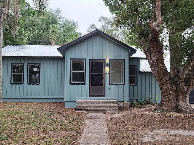 view of front facade with entry steps, board and batten siding, and metal roof