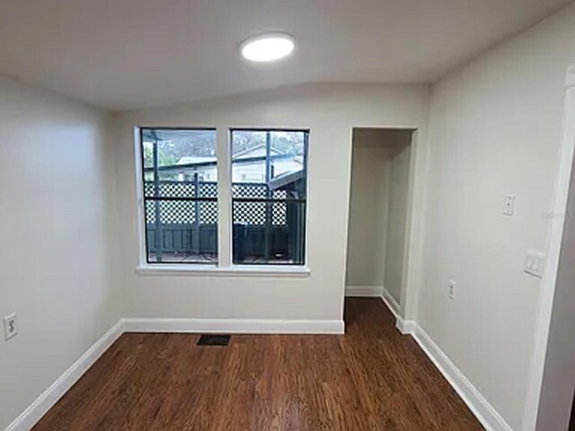 unfurnished room with dark hardwood / wood-style floors and lofted ceiling