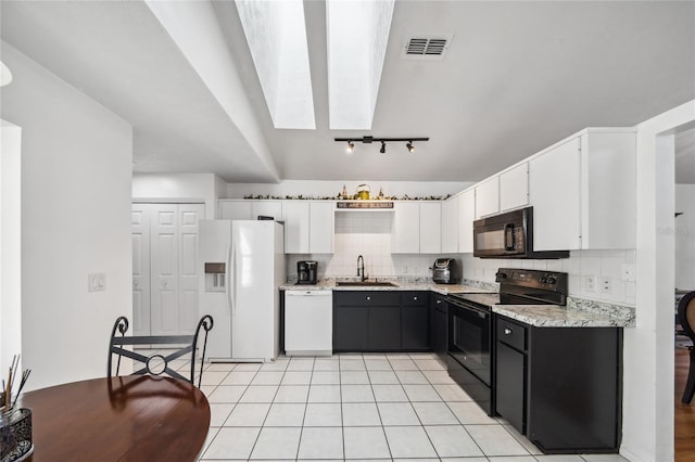 kitchen featuring rail lighting, tasteful backsplash, black appliances, white cabinets, and light tile patterned flooring