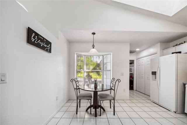 dining area with vaulted ceiling and light tile patterned floors