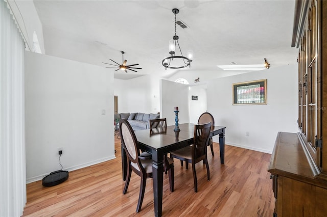 dining area featuring light hardwood / wood-style floors, ceiling fan with notable chandelier, and vaulted ceiling