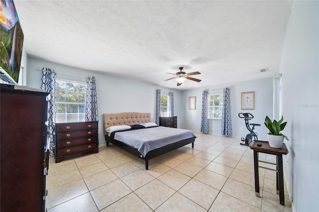 tiled bedroom with ceiling fan and a textured ceiling