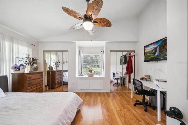 bedroom with ceiling fan, vaulted ceiling, light wood-type flooring, and multiple closets