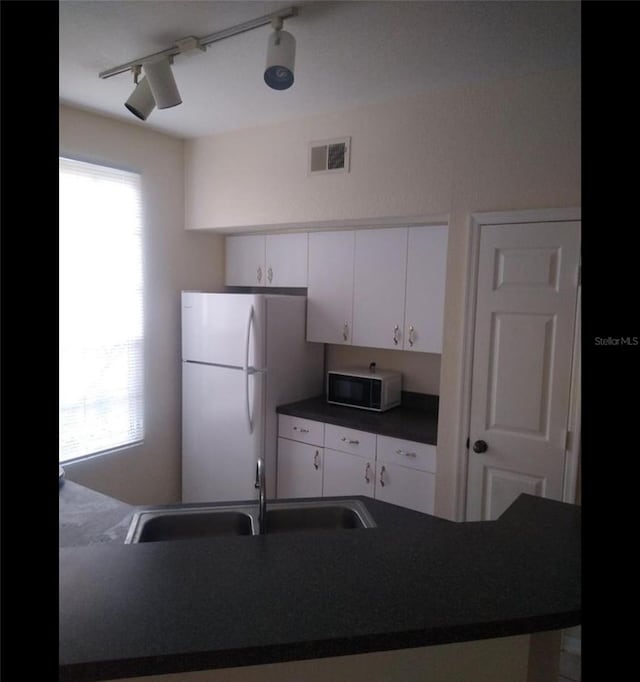 kitchen with sink, track lighting, white cabinetry, and white appliances