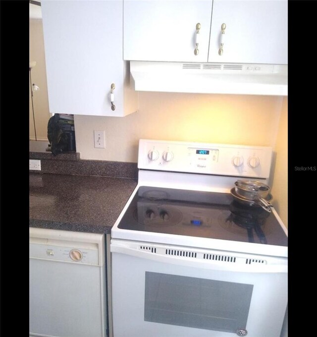 kitchen with extractor fan, white appliances, and white cabinets