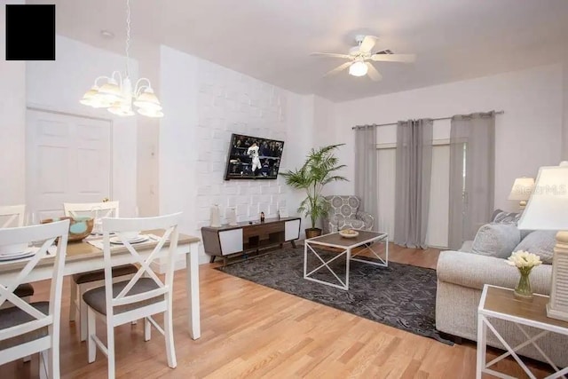 living room with ceiling fan with notable chandelier and hardwood / wood-style flooring