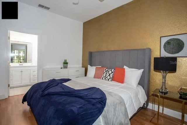 bedroom featuring sink, vaulted ceiling, light hardwood / wood-style flooring, connected bathroom, and ceiling fan