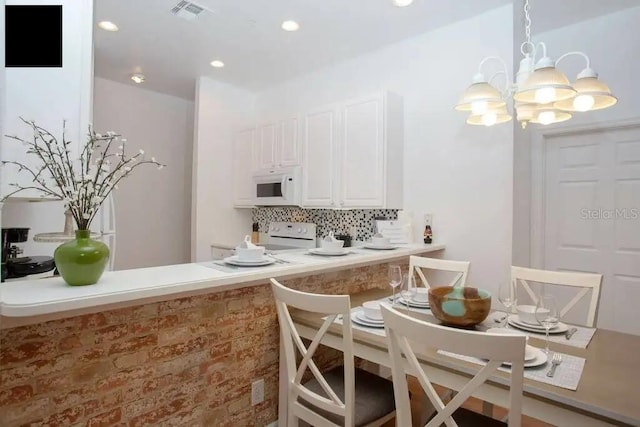 kitchen featuring a notable chandelier, decorative backsplash, stove, and white cabinets