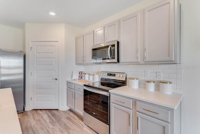 kitchen with backsplash, light wood-type flooring, and appliances with stainless steel finishes