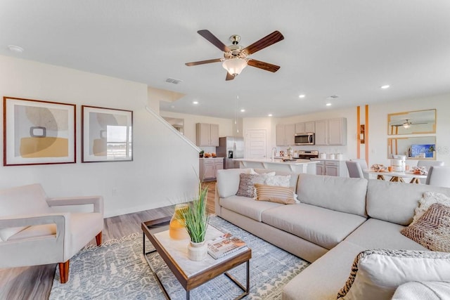 living room featuring ceiling fan, sink, and light hardwood / wood-style flooring