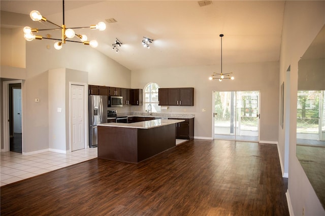 kitchen with appliances with stainless steel finishes, a center island, light hardwood / wood-style flooring, and dark brown cabinets