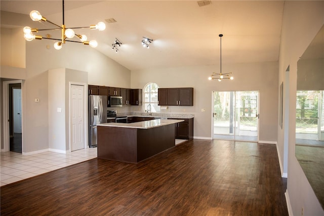 kitchen featuring a notable chandelier, stainless steel appliances, a kitchen island, open floor plan, and light countertops