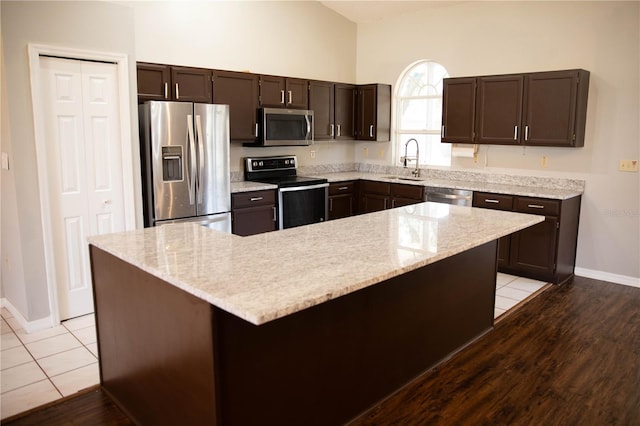 kitchen with light hardwood / wood-style floors, appliances with stainless steel finishes, dark brown cabinetry, and a kitchen island