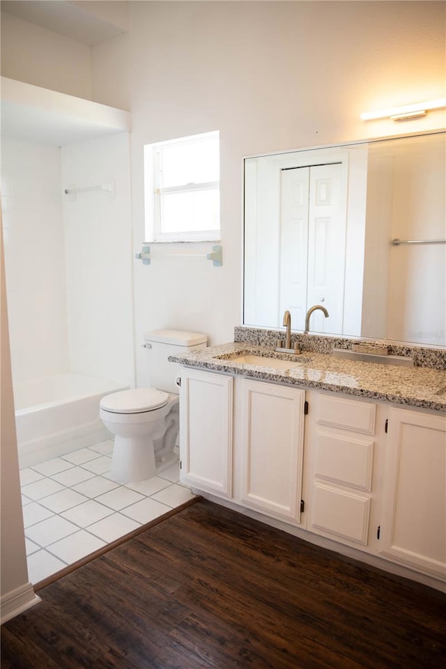 full bathroom with toilet,  shower combination, vanity, and wood-type flooring