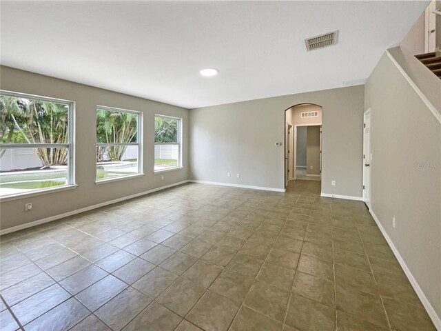 spare room with tile patterned flooring, visible vents, arched walkways, and baseboards