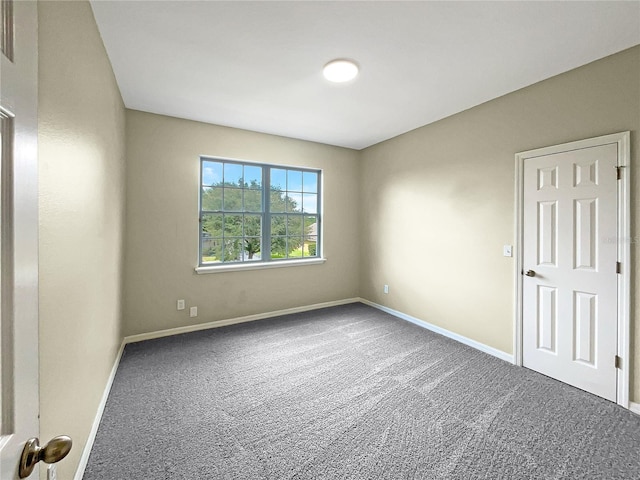 carpeted empty room featuring baseboards