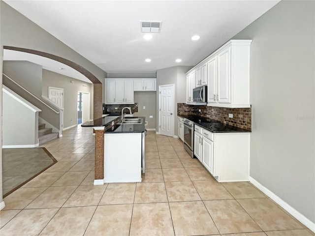 kitchen featuring appliances with stainless steel finishes, dark countertops, white cabinets, and visible vents