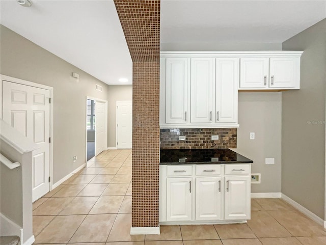 kitchen featuring dark countertops, white cabinets, decorative backsplash, and light tile patterned floors