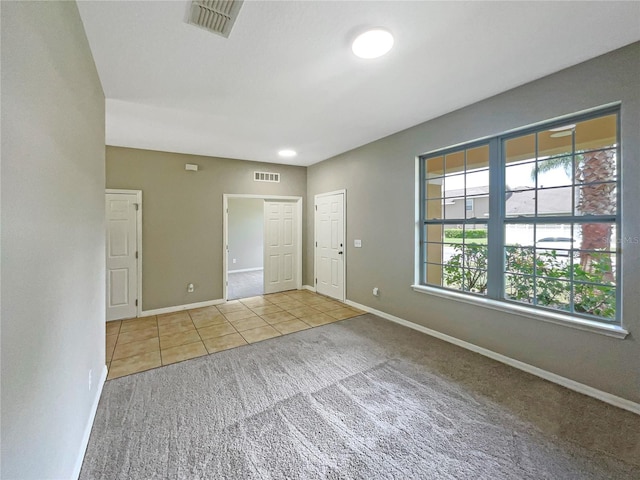 unfurnished room featuring baseboards, visible vents, and light colored carpet