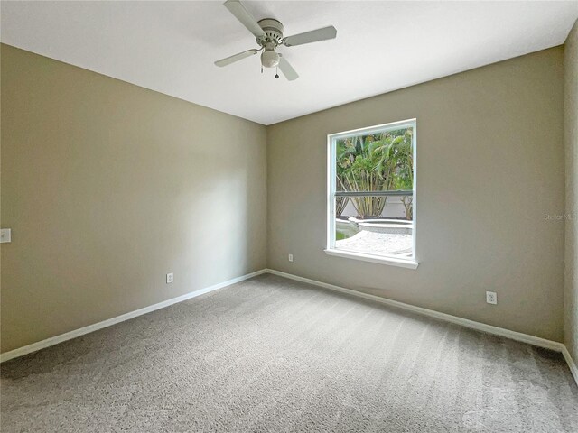 carpeted empty room with ceiling fan and baseboards