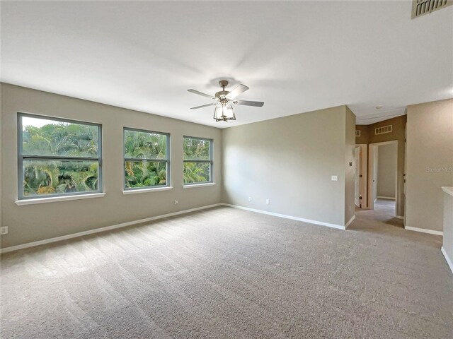 spare room with baseboards, ceiling fan, visible vents, and light colored carpet