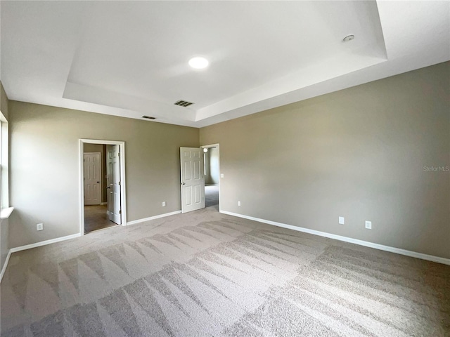 unfurnished bedroom featuring baseboards, visible vents, and a raised ceiling