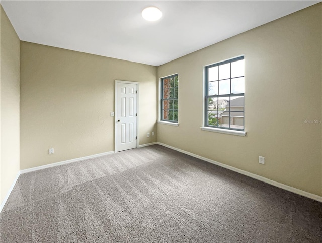 carpeted empty room featuring baseboards