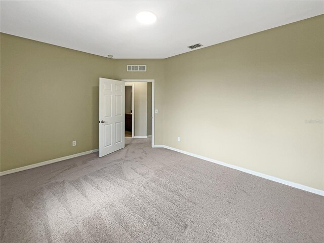 carpeted spare room featuring visible vents and baseboards